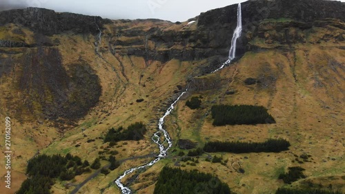 Aerial video going towards the amazing waterfall Bjarnarfoss located in the high mountains of Iceland. photo