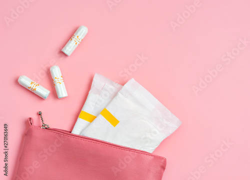 Sanitary pads and tampons in cosmetic bag on pink background. Concept of critical days, menstruation photo