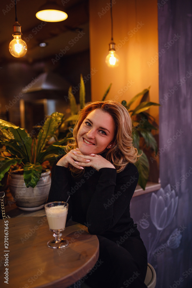 Smiling woman in a good mood with cup of coffee sitting in cafe. Smiling woman in a good mood with cup of coffee sitting in cafe.