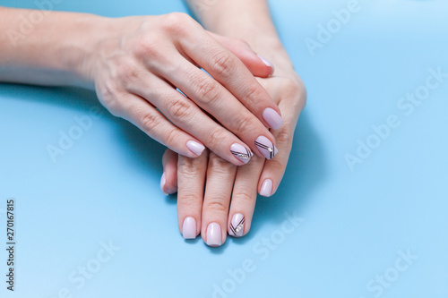 Beautiful female hands and a fashionable manicure on a blue background