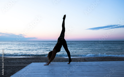 woman doing yoga at sunrise on the sea, silhouette of yoga poses