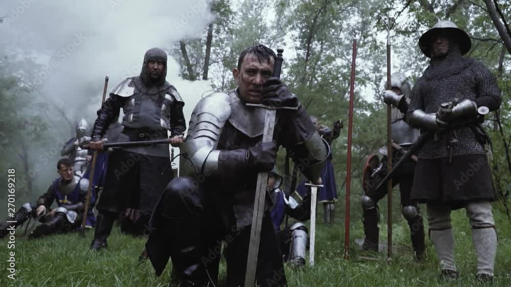 Medieval warriors in metal chainplate armor in the forest under rain Medieval warriors in metal chainplate armor in the forest under rain
