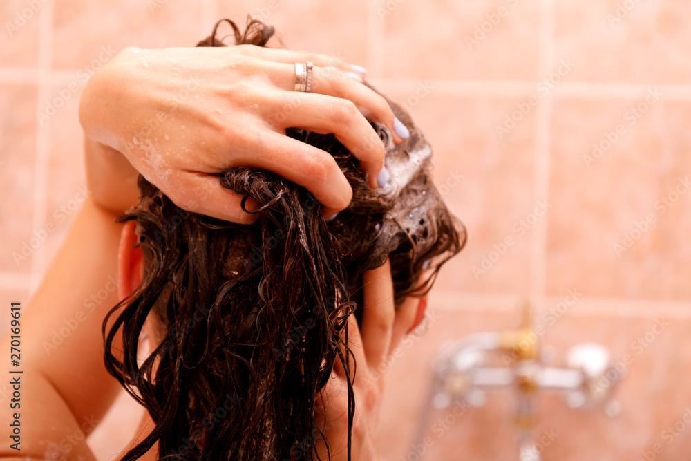 Naklejka premium Young woman washing hair in shower. 