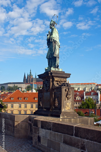 Statue of St John of Nepomuk on the Charles Bridge with St. Vitus Cathedral in background.