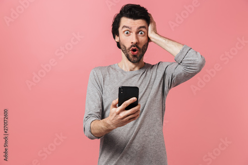 Excited young man isolated over pink wall background using mobile phone. © Drobot Dean