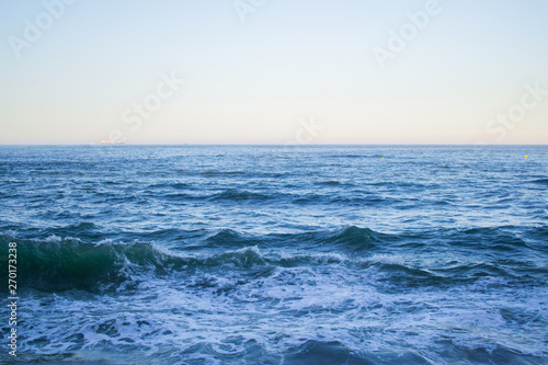 Sea waves splashing in Cantabrian Sea with clear blue water and skyline. Natural background
