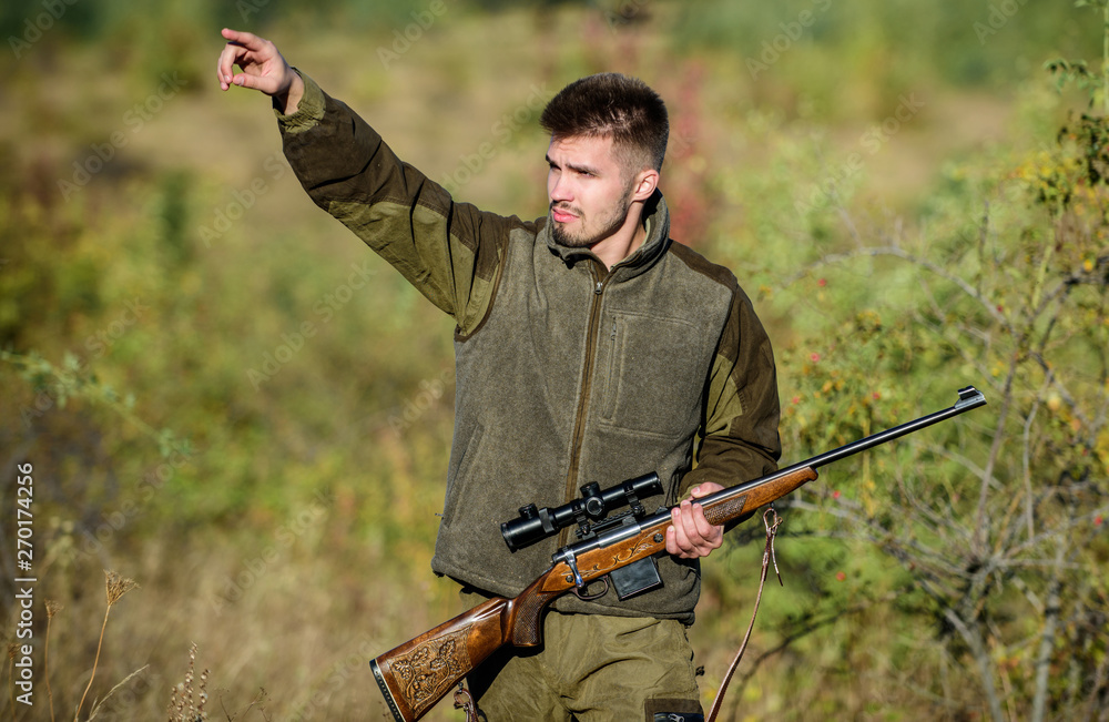 Fototapeta premium Man brutal unshaved gamekeeper nature background. Hunting permit. Hunter hold rifle. Hunting is brutal masculine hobby. Hunting and trapping seasons. Bearded serious hunter spend leisure hunting