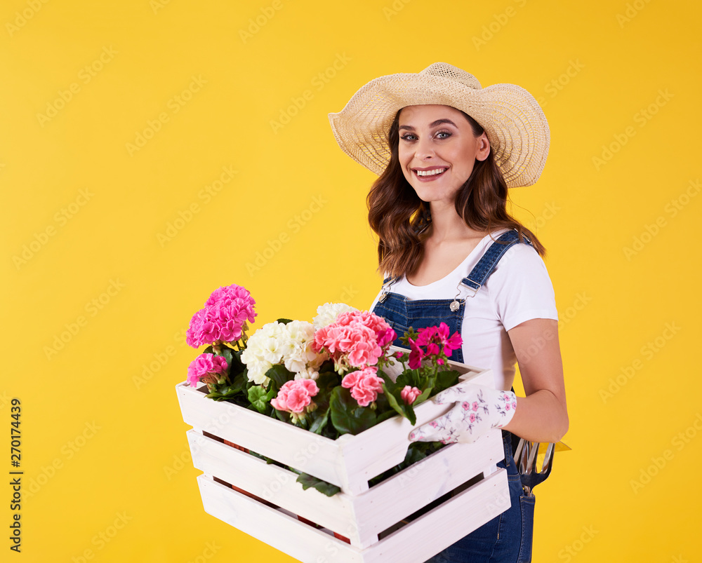 Smiling woman holding wooden crate with flowers Smiling woman holding wooden crate with flowers