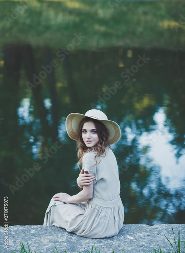 romantic portrait of a girl in a hat on the background of the river