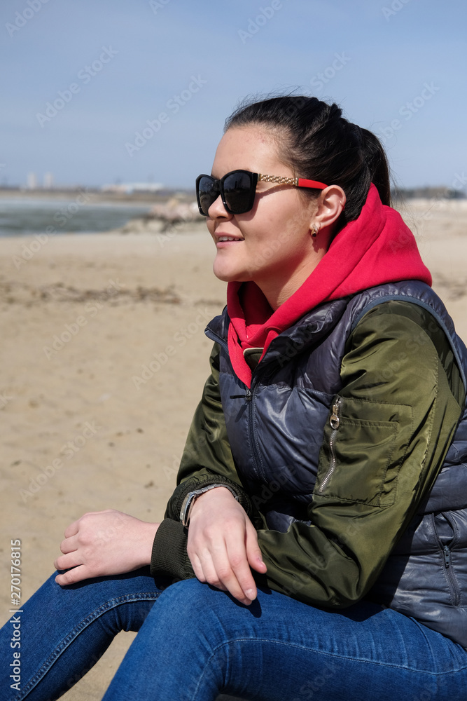 Woman in a red hoodie walking on the beach. Close-up portrait.