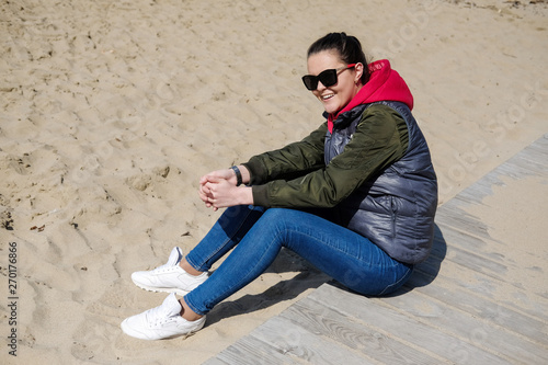 Woman in a red hoodie walking on the beach. Close-up portrait. © evelinphoto