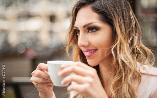 Portrait of woman sitting in outdoor cafe and drinking coffee