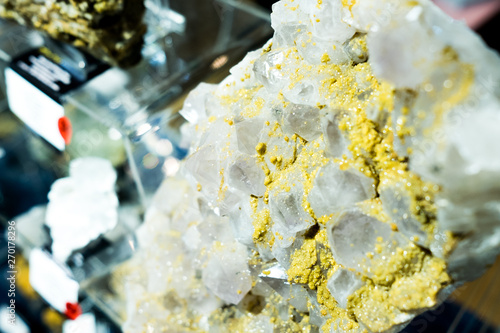 close up of piece of clear and golden quartz siderite exhibited in minerals trade show behind glass photo