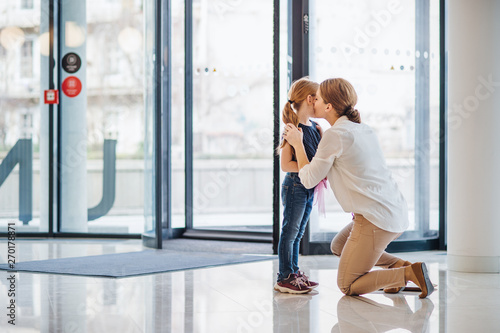 A mother saying goodbye to small daughter in office building, nursery concept.