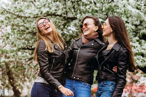 Best friends girls having fun, joy. Lifestyle. Beautiful young women in sunglasses dressed in the nice clothes smiling on a sunny day. photos of girls against the background of flowering trees