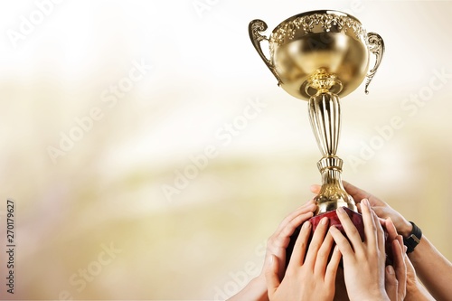 Hands holding golden trophy on light background