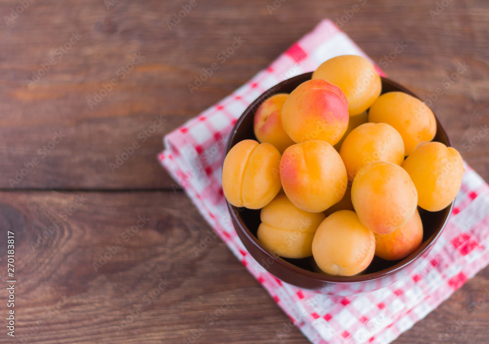 ripe fresh apricots in a bowl on a wooden table