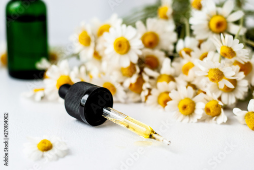 Essential aroma oil with camomile on white background.