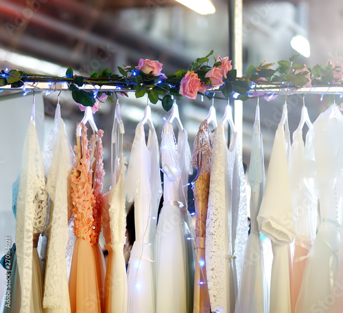 Few elegant wedding, bridesmaid ,evening, ball gown or prom dresses on a hanger in a bridal shop.