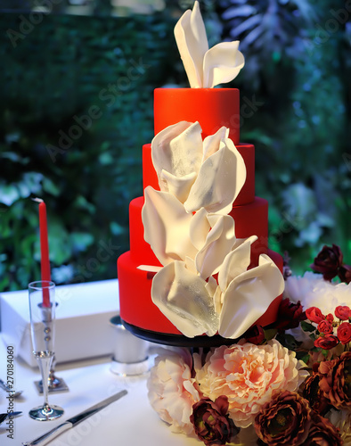 Traditional anniversary/wedding multi-layer cake. Beautiful delicious red sweet dessert decorated with white flowers