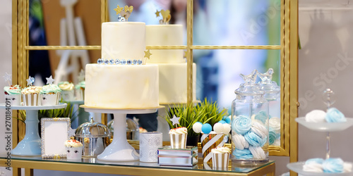 Traditional anniversary/wedding multi-layer cake and delicious sweet dessert at blue and white tones - cupcakes, marshmallow, vanilla cake pops. Stylish sweet table.