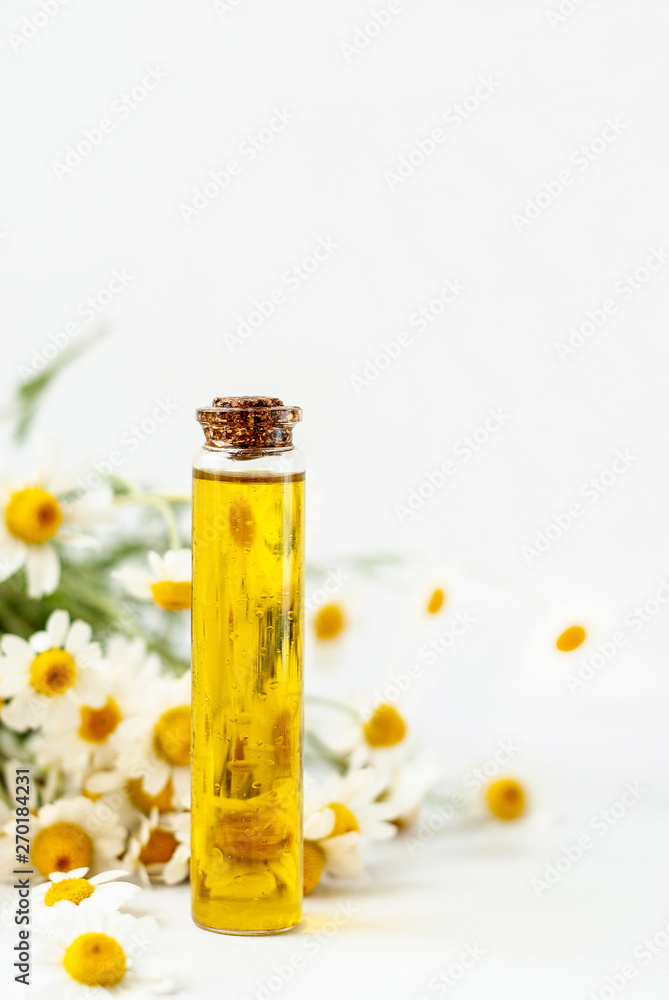 Essential aroma oil with camomile on wooden background. Selective focus. Essential aroma oil with camomile on wooden background. Selective focus.