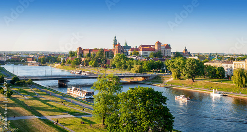 Poland. Krakow aerial panorama with historic royal Wawel castle and cathedral, Vistula river with a bridge, boats, on board restaurant. Promenades and parks along the riversides. Sunset light