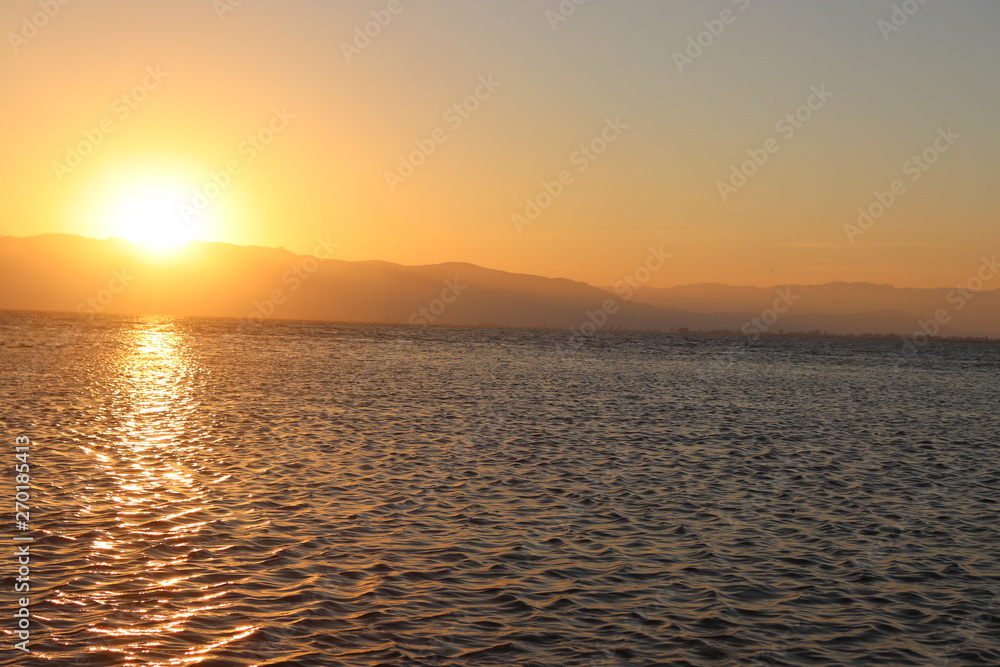 Naklejka premium Atardecer tras las montañas en un lago