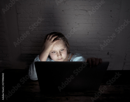 Sad young girl with laptop suffering bullying and harassment online. Cyber bullying victim