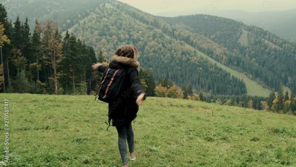 Camera follows young girl hiker running through a valley of mountains landscape, jumping, smiling, raises arms into air. Outdoor activity. Lifestyle adventure. Back view, toning, 4k Camera follows young girl hiker running through a valley of mountains landscape, jumping, smiling, raises arms into air. Outdoor activity. Lifestyle adventure. Back view, toning, 4k