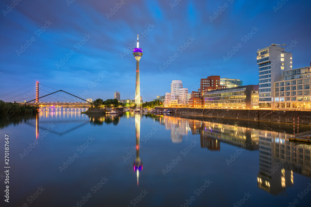 Dusseldorf, Germany. Cityscape image of Düsseldorf, Germany with the Media Harbour and reflection of the city in the Rhine river, during twilight blue hour.