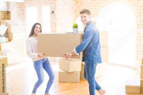 Beautiful young couple smiling in love holding a big cardboard box, happy for moving to a new home © Krakenimages.com