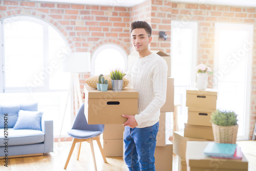 Young man smiling holdig cardboard box, happy moving to a new house © Krakenimages.com