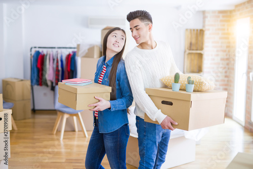 Beautiful young asian couple looking happy holding cardboard boxes, smiling excited moving to a new home © Krakenimages.com