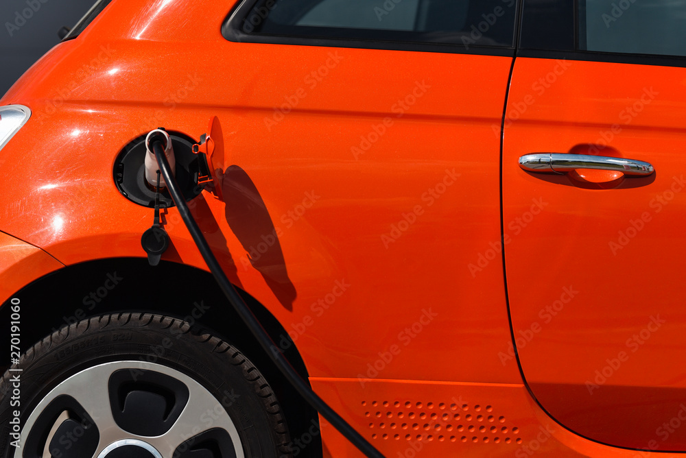 orange electric car on charge in closeup