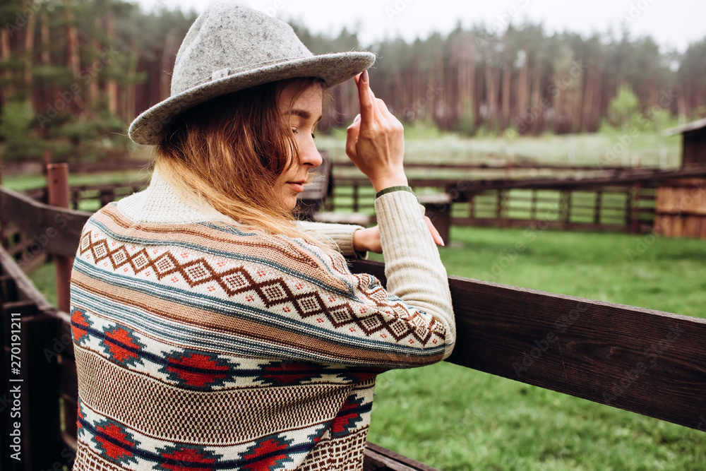 Girl in clothes with ethnic patterns posing in nature background. Portrait of smiling young woman in boho hat. close up portrait of a girl in a hat  in rainy day.