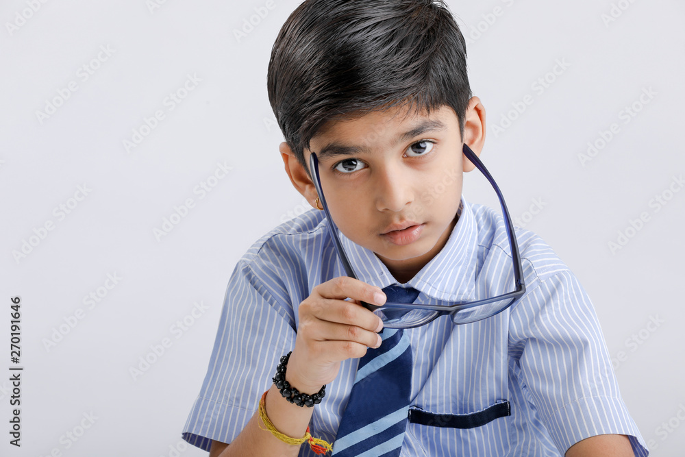 Cute little Indian/Asian school boy with spectacles reading book over white background Cute little Indian/Asian school boy with spectacles reading book over white background