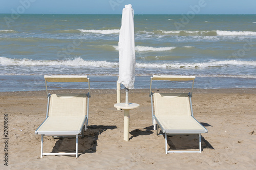 Fototapeta Naklejka Na Ścianę i Meble -  Sunbed and parasol on the Sand Beach with the Sea in Italy.