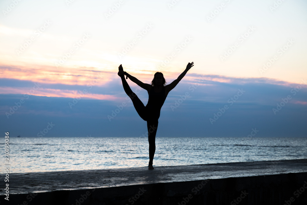 unrecognizable senoir woman with beautiful body doing yoga at sunrise on the sea, silhouette of yoga poses