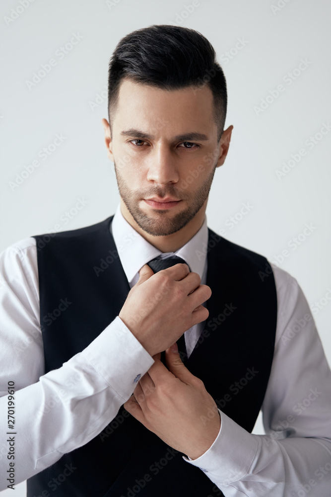 Young handsome man in elegant suit adjust his necktie Young handsome man in elegant suit adjust his necktie