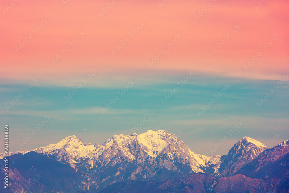 Mountain landscape in the evening. Mountain range covered with snow against the gradient sunset sky