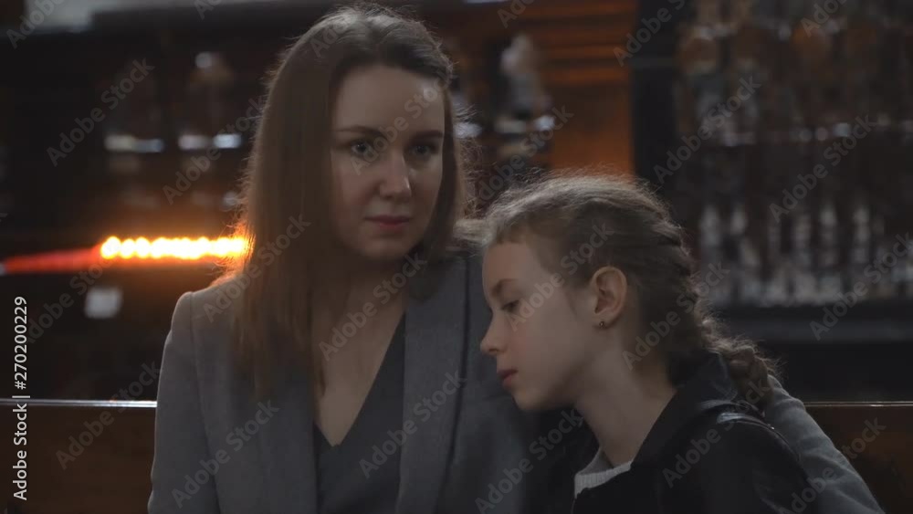 Woman and her daughter are sitting on a bench in the church. Woman and her daughter are sitting on a bench in the church.