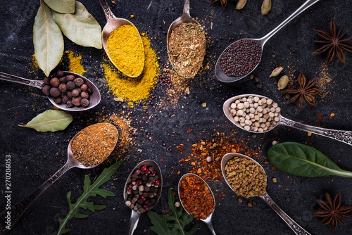 Fototapeta Naklejka Na Ścianę i Meble -  Spices and herbs on spoons in  a black background, top view.  Indian cuisine.