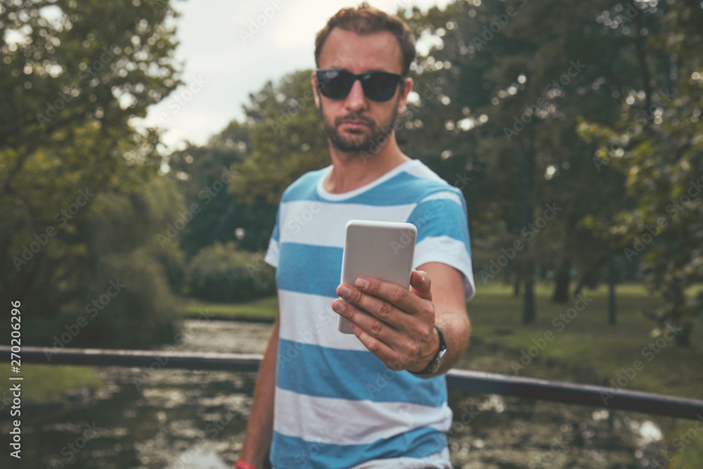 Fototapeta premium Trendy man using cellphone outdoors.
