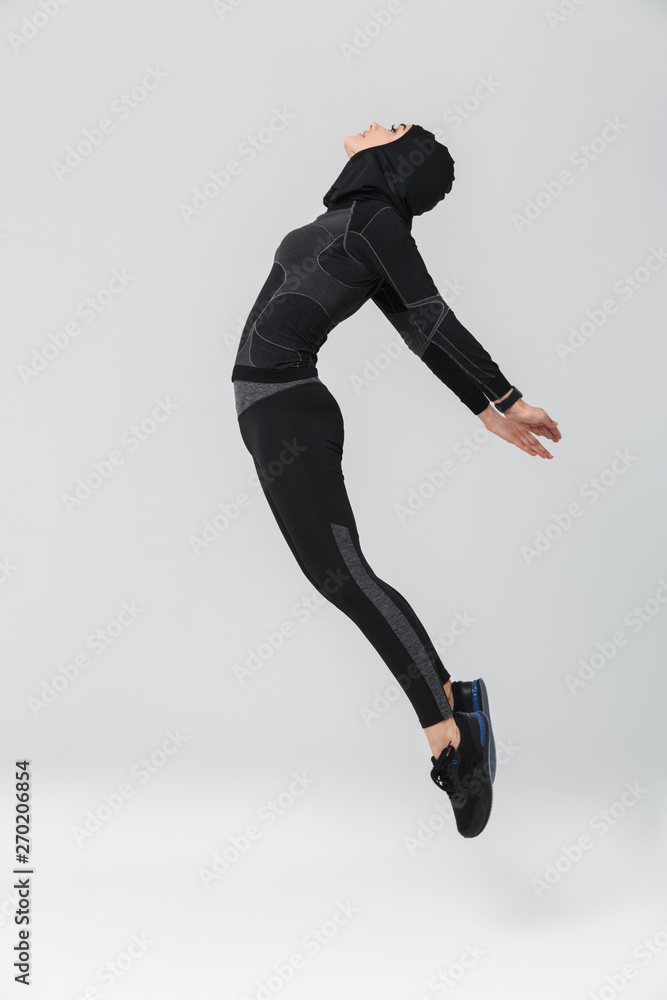 Woman fitness muslim posing running jumping isolated over white wall background.