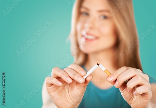 Young woman breaking cigarette  on background