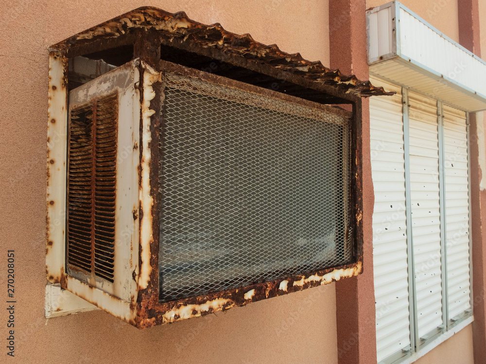 Old window air conditioner and window with closed rolling shutter Stock