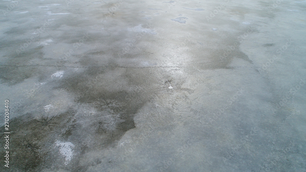 ice surface on the water in the spring with traces of fishermen and people