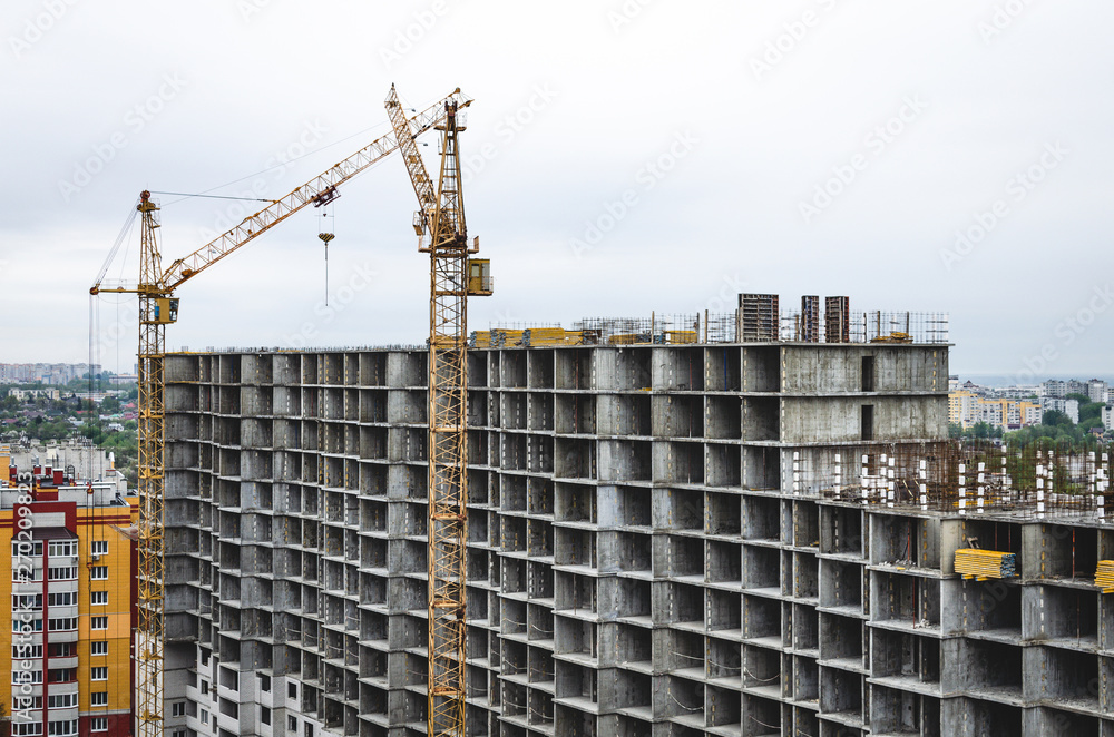 Two tower cranes on the construction of a residential house. Building a new residential area Two tower cranes on the construction of a residential house. Building a new residential area