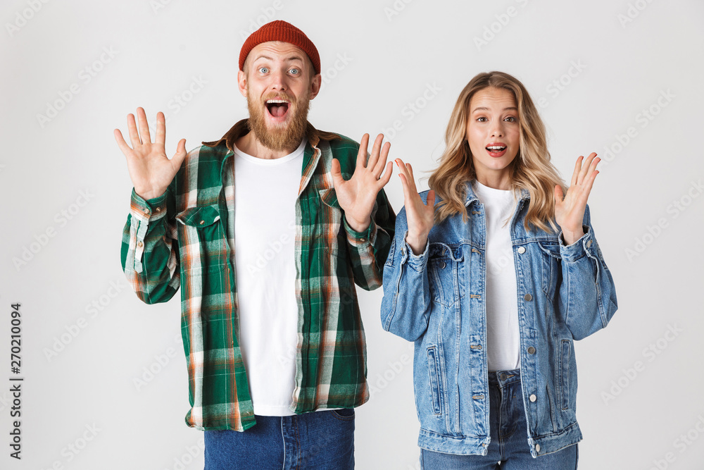 Obraz premium Shocked emotional young loving couple posing isolated over white wall background.